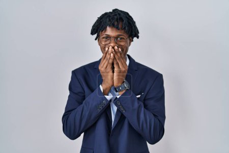 Foto de Young african man with dreadlocks wearing business jacket over white background laughing and embarrassed giggle covering mouth with hands, gossip and scandal concept - Imagen libre de derechos