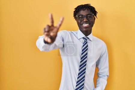 Téléchargez les photos : African man with dreadlocks standing over yellow background smiling looking to the camera showing fingers doing victory sign. number two. - en image libre de droit