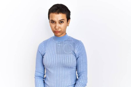 Foto de Young hispanic woman with short hair standing over isolated background skeptic and nervous, frowning upset because of problem. negative person. - Imagen libre de derechos