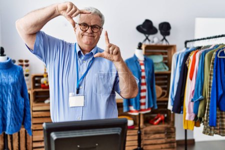 Photo for Senior man with grey hair working as manager at retail boutique smiling making frame with hands and fingers with happy face. creativity and photography concept. - Royalty Free Image