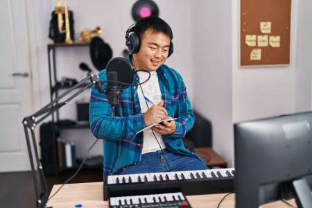 Photo for Young chinese man singer composing song at music studio - Royalty Free Image