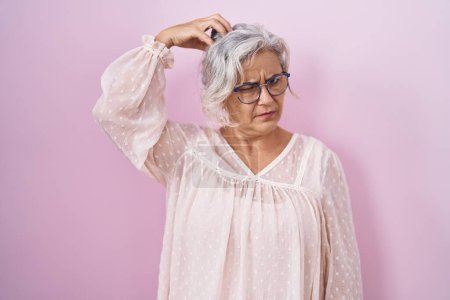 Photo for Middle age woman with grey hair standing over pink background confuse and wonder about question. uncertain with doubt, thinking with hand on head. pensive concept. - Royalty Free Image