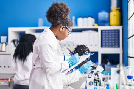 Téléchargez les photos : African american friends scientists writing on clipboard working at laboratory - en image libre de droit