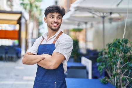 Photo pour Young arab man waiter standing with arms crossed gesture at restaurant - image libre de droit