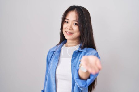 Téléchargez les photos : Jeune femme chinoise debout sur fond blanc souriant joyeuse offrant main de paume donnant assistance et acceptation. - en image libre de droit