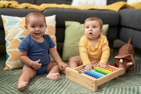 Foto de Dos niños jugando con ábaco sentados en el suelo en casa - Imagen libre de derechos