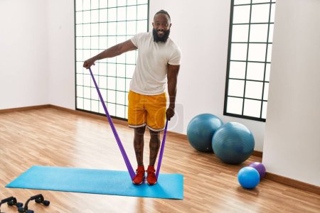 Photo for Young african american man smiling confident training with elastic band at sport center - Royalty Free Image