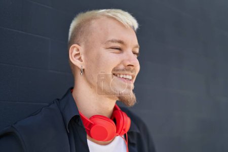 Foto de Joven hombre caucásico sonriendo confiado usando auriculares sobre fondo negro aislado - Imagen libre de derechos