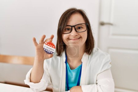 Photo for Brunette woman with down syndrome smiling holding vote badge at election room - Royalty Free Image