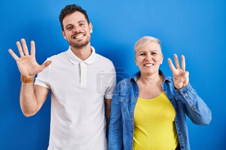 Photo for Young brazilian mother and son standing over blue background showing and pointing up with fingers number eight while smiling confident and happy. - Royalty Free Image