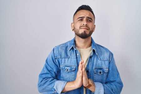 Photo for Young hispanic man standing over isolated background begging and praying with hands together with hope expression on face very emotional and worried. begging. - Royalty Free Image