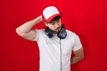 Photo for Hispanic man with beard wearing gamer hat and headphones confuse and wondering about question. uncertain with doubt, thinking with hand on head. pensive concept. - Royalty Free Image
