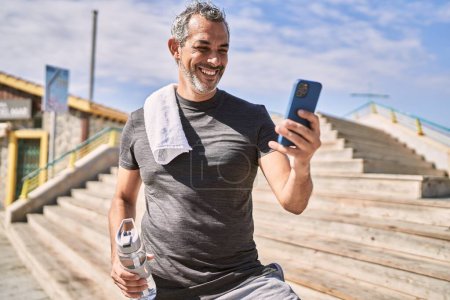 Photo for Middle age hispanic man wearing sportswear using smartphone at street - Royalty Free Image