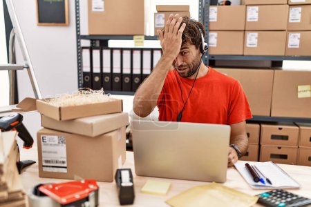 Foto de Young hispanic call center agent man working at warehouse surprised with hand on head for mistake, remember error. forgot, bad memory concept. - Imagen libre de derechos