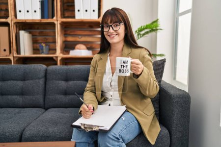 Photo for Young hispanic woman drinking from i am the boss coffee cup looking positive and happy standing and smiling with a confident smile showing teeth - Royalty Free Image