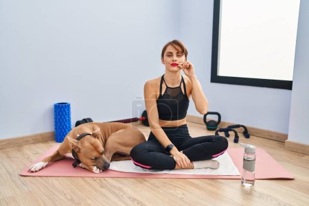 Photo for Young beautiful woman sitting on yoga mat mouth and lips shut as zip with fingers. secret and silent, taboo talking - Royalty Free Image