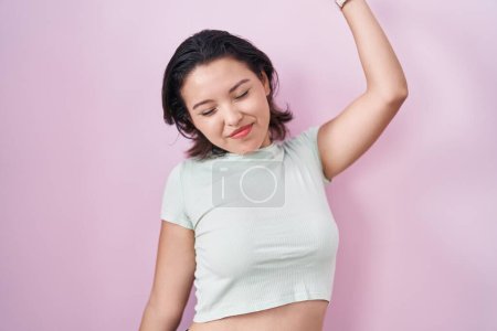 Photo for Hispanic young woman standing over pink background stretching back, tired and relaxed, sleepy and yawning for early morning - Royalty Free Image