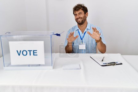 Photo for Young handsome man at political election sitting by ballot disgusted expression, displeased and fearful doing disgust face because aversion reaction. with hands raised - Royalty Free Image