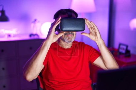 Téléchargez les photos : Homme moyen streamer jouer à un jeu vidéo en utilisant des lunettes de réalité virtuelle à la salle de jeux - en image libre de droit