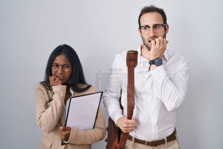 Photo for Interracial business couple wearing glasses looking stressed and nervous with hands on mouth biting nails. anxiety problem. - Royalty Free Image