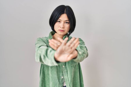 Téléchargez les photos : Young asian woman standing over white background rejection expression crossing arms and palms doing negative sign, angry face - en image libre de droit