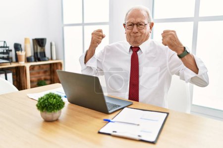 Photo for Senior man working at the office using computer laptop showing arms muscles smiling proud. fitness concept. - Royalty Free Image