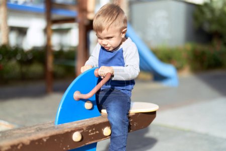 Téléchargez les photos : Adorable bambin jouant sur swing au parc aire de jeux - en image libre de droit