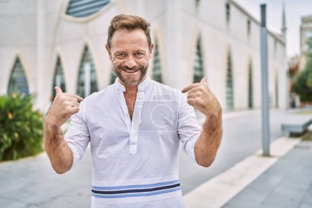 Photo for Middle age man outdoor at the city looking confident with smile on face, pointing oneself with fingers proud and happy. - Royalty Free Image