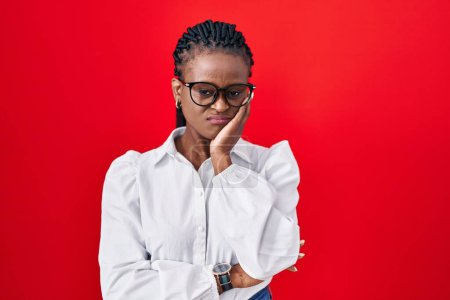 Photo for African woman with braids standing over red background thinking looking tired and bored with depression problems with crossed arms. - Royalty Free Image