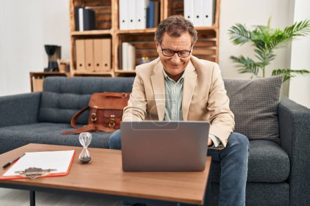 Téléchargez les photos : Homme d'âge moyen ayant session de psychologie en utilisant un ordinateur portable à la clinique - en image libre de droit