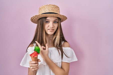Photo for Teenager girl holding ice cream pointing aside worried and nervous with forefinger, concerned and surprised expression - Royalty Free Image