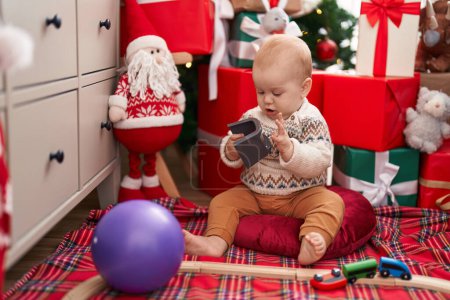 Photo for Adorable caucasian baby playing with train toy sitting on floor by christmas gifts at home - Royalty Free Image