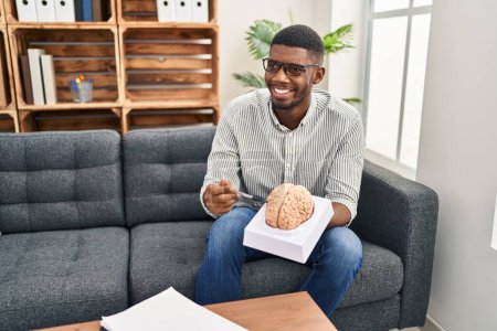 Photo for Young african american man psychologist holding brain at clinic - Royalty Free Image