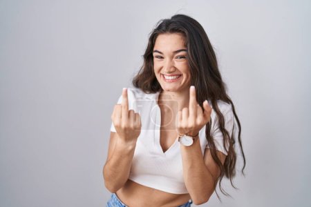 Foto de Young teenager girl standing over white background showing middle finger doing fuck you bad expression, provocation and rude attitude. screaming excited - Imagen libre de derechos