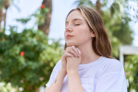 Téléchargez les photos : Young caucasian woman praying with closed eyes at park - en image libre de droit