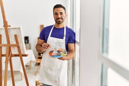 Photo for Young hispanic man smiling confident mixing color on palette at art studio - Royalty Free Image