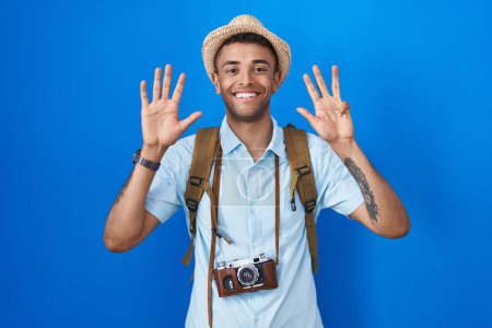 Téléchargez les photos : Brazilian young man holding vintage camera showing and pointing up with fingers number nine while smiling confident and happy. - en image libre de droit