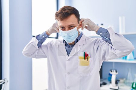 Photo for Young man scientist wearing medical mask standing at laboratory - Royalty Free Image
