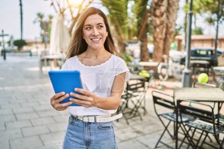 Téléchargez les photos : Young hispanic woman smiling confident using touchpad at street - en image libre de droit