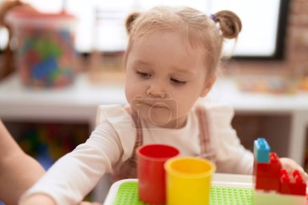 Téléchargez les photos : Adorable fille caucasienne jouer avec jouer cuisine assis sur la table à la maternelle - en image libre de droit