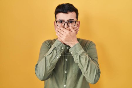 Photo for Non binary person standing over yellow background shocked covering mouth with hands for mistake. secret concept. - Royalty Free Image