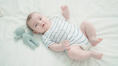 Photo for Adorable caucasian baby smiling confident lying on bed with at bedroom - Royalty Free Image
