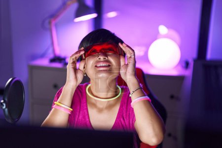 Téléchargez les photos : Middle age chinese woman streamer playing video game using virtual reality glasses at gaming room - en image libre de droit