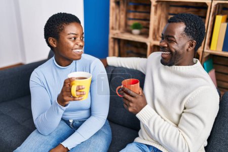Photo for Man and woman couple drinking coffee sitting on sofa at home - Royalty Free Image