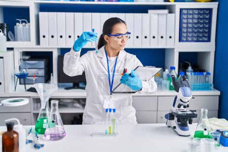 Photo for Young hispanic woman scientist holding test tube at laboratory - Royalty Free Image