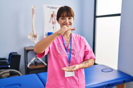 Photo for Young brunette woman working at rehabilitation clinic gesturing with hands showing big and large size sign, measure symbol. smiling looking at the camera. measuring concept. - Royalty Free Image