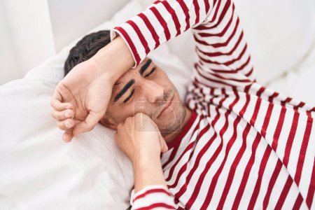 Photo for Young hispanic man stressed lying on bed at bedroom - Royalty Free Image