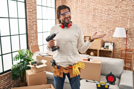 Photo for Handsome middle age man holding screwdriver at new home pointing aside with hands open palms showing copy space, presenting advertisement smiling excited happy - Royalty Free Image
