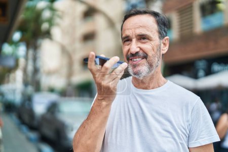 Foto de Hombre de mediana edad sonriendo confiado hablando en el teléfono inteligente en la calle - Imagen libre de derechos