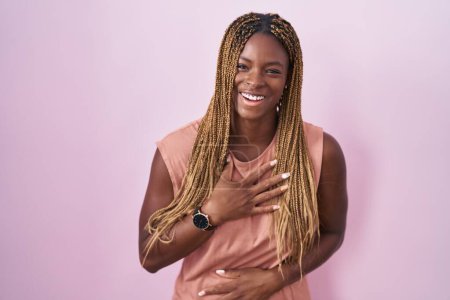 Photo for African american woman with braided hair standing over pink background smiling and laughing hard out loud because funny crazy joke with hands on body. - Royalty Free Image